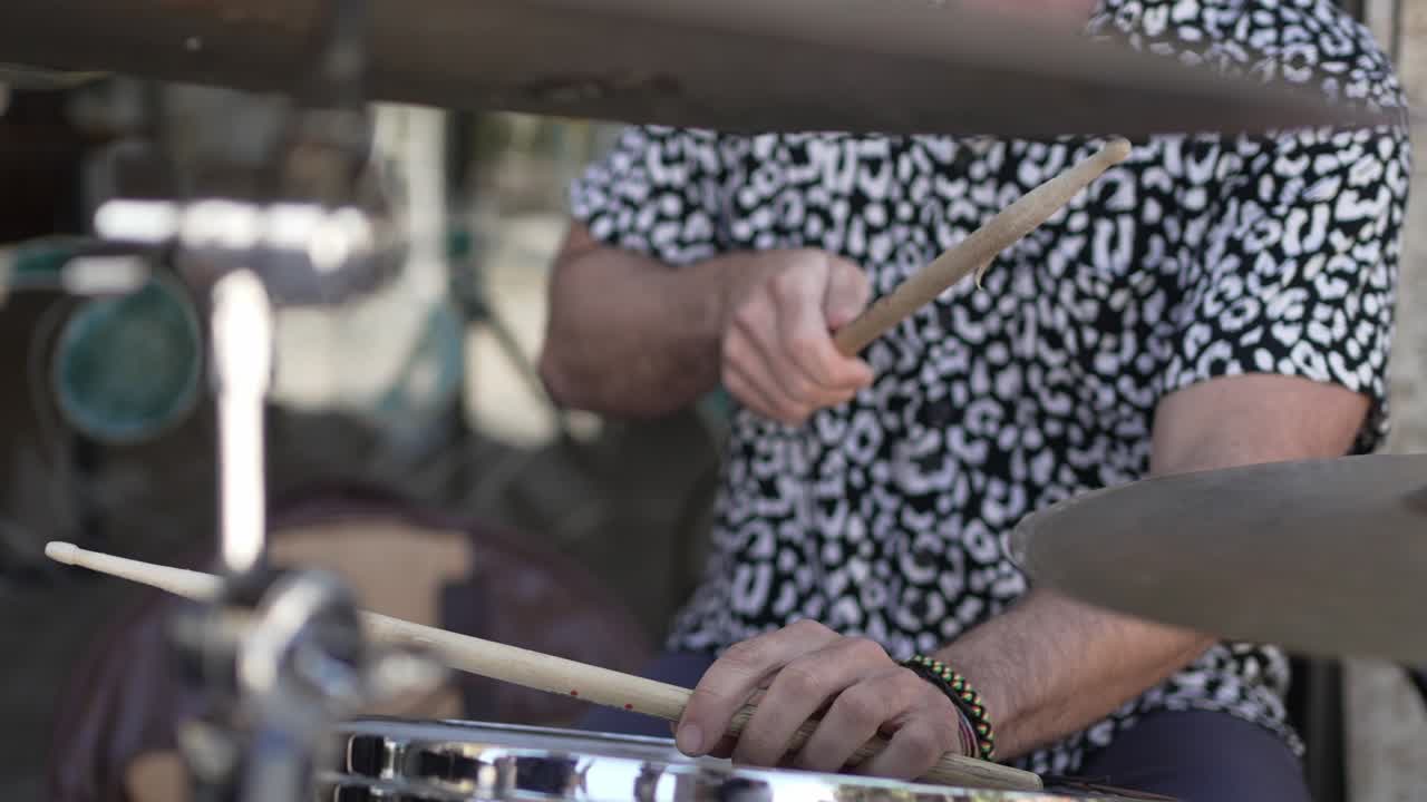 Close up of drummer with drumsticks and cymbals in vibrant outdoor setting