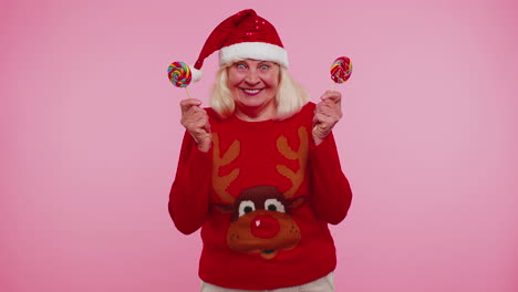 Grandmother-in-Christmas-sweater-holding-candy-striped-lollipops-hiding-behind-them-fooling-around