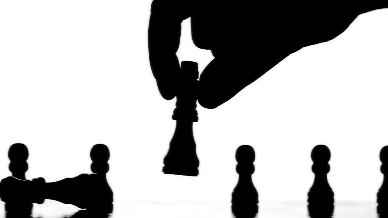 Hand knocking over chess piece 