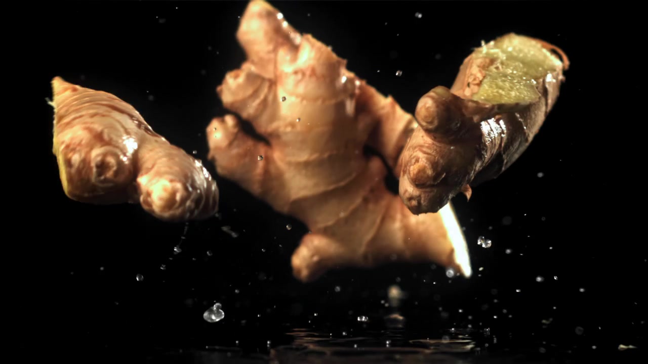Fresh Ginger Root Falling and Splashing into Water on Black Background