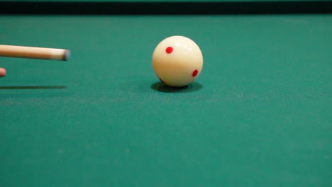 slow motion billiards close up of cue ball as person breaks the rack on pool table with green felt and the cue stick bending and both solid and stiped balls rolling into frame