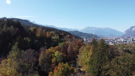 Alpine-forest-with-an-aerial-view-and-we-see-Innsbruck-in-the-middle-of-this-alpine-valley-with-the-alpine-mountains-in-the-background-of-this-region-of-Tyrol-in-Austria