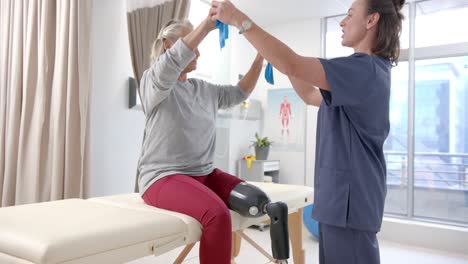 caucasian female physiotherapist and female senior patient with prosthetic leg exercising