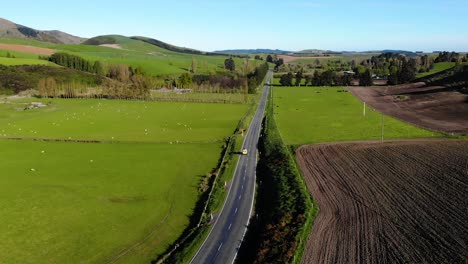 Aerial-view-of-car-driving-on-a-country-road-in-a-beautiful-New-Zealand-landscape