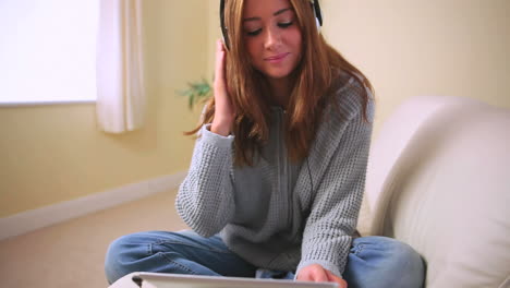 Cheerful-attractive-brunette-sitting-on-couch-listening-to-music