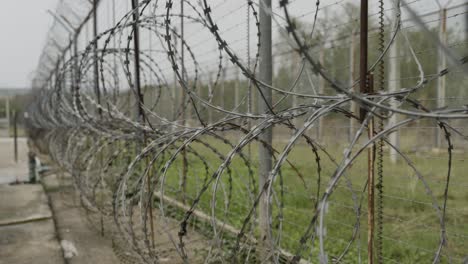 high security razor wire fence inside a prison, barbed wire metal fence along the border protection, smooth cinematic shot