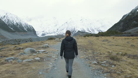 siguiente toma de una mujer caminando entre montañas nevadas en un frío día de invierno en la isla sur de nueva zelanda