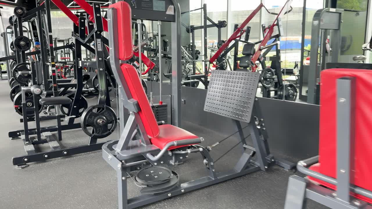 A well-equipped gym in Bangkok featuring modern workout machines with red accents, captured in bright, natural lighting