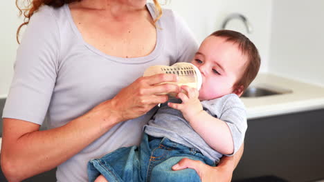 mother feeding her baby boy his bottle