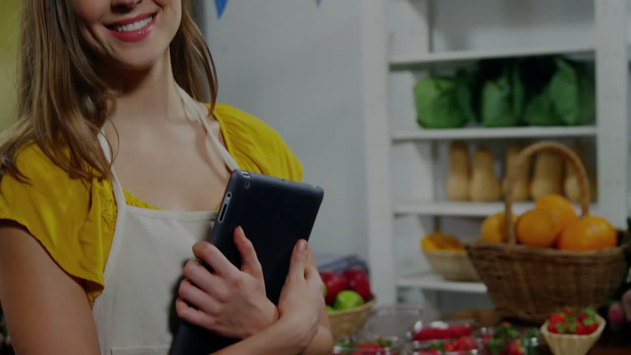 Market seller holding tablet starting data graphs overlaying body while tracking produce sales