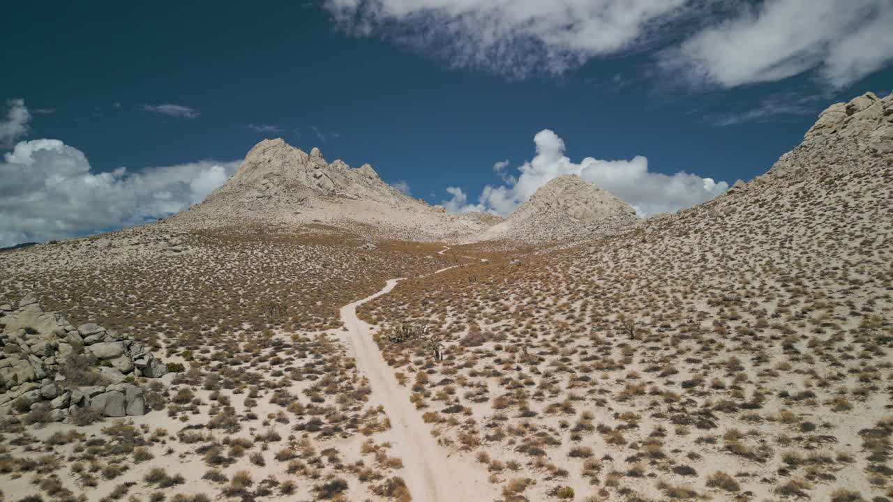 A drone slowly climbs to follow a sandy desert trail in the Eastern Sierra Nevada range