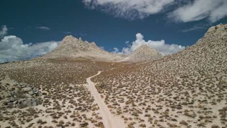 a drone slowly climbs to follow a sandy desert trail in the eastern sierra nevada range