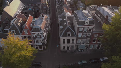 aerial tilt showing canal houses in medieval dutch city of utrecht at sunrise revealing the wider cityscape and looking into the deserted early morning street