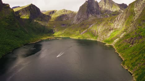 Aerial-view-of-a-boat-leaving-Djupfjorden-near-Reine-in-the-Lofoten-Islands,-Norway