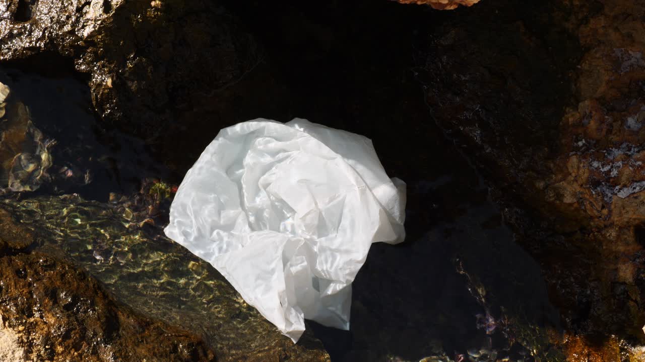 Sacchetto di plastica incastrato tra le rocce sulla costa