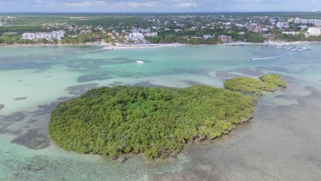 tomada de un avión no tripulado que muestra una isla tropical, un jet ski de crucero, la playa de arena de boca chica y la ciudad de santo domingo en el fondo