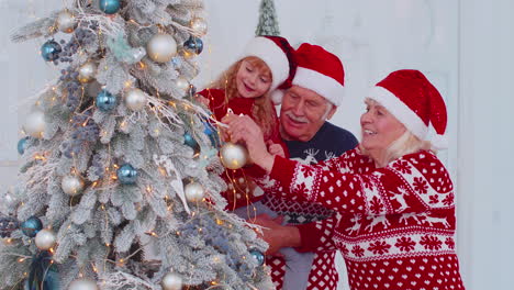 Abuelos-Felices,-Nieta-Niño-Pequeño-Colgando-Bolas-Decorando-El-árbol-De-Navidad-Celebrando