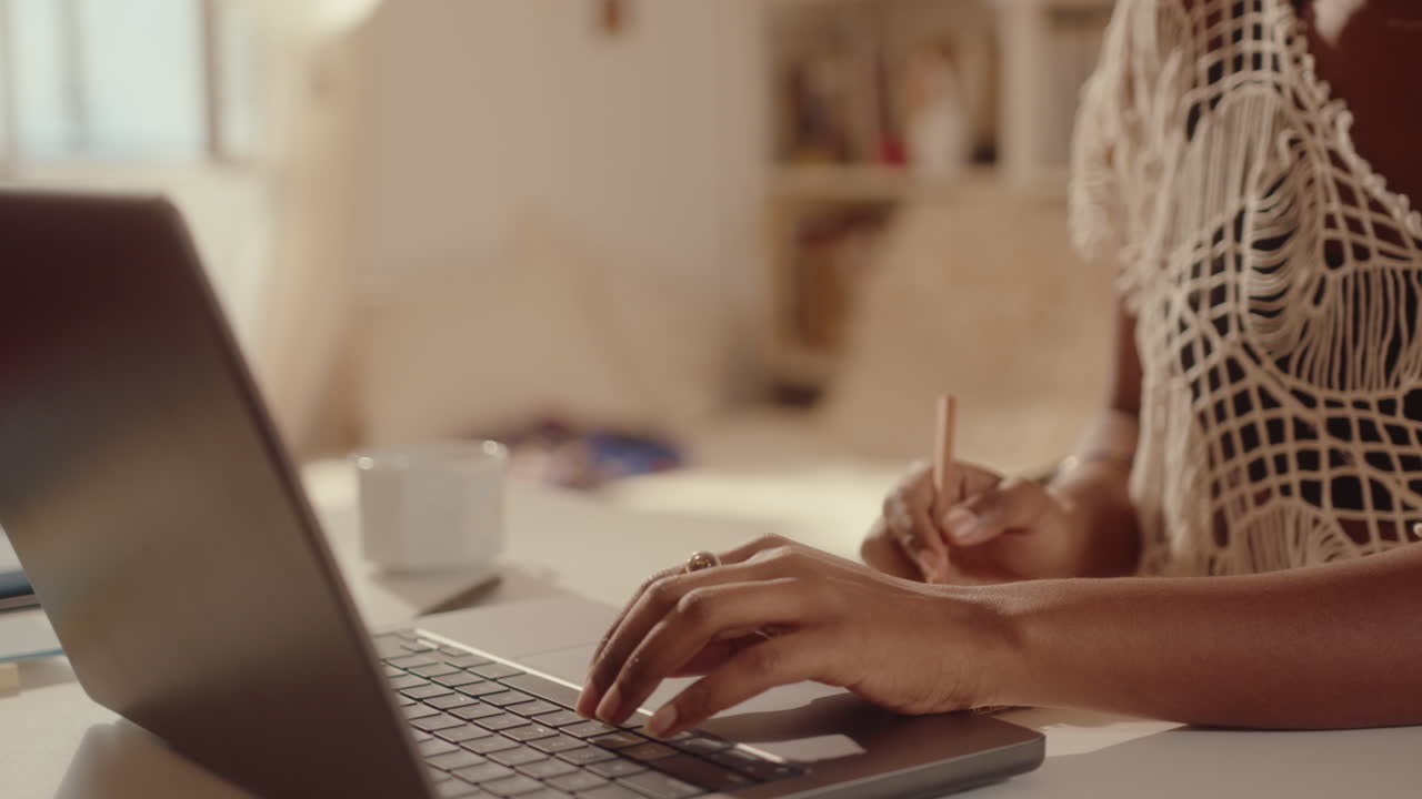 Hands of Girl Using Laptop and Making Notes at Desk