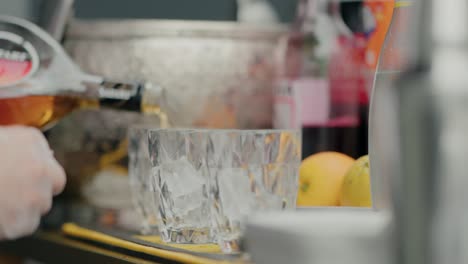 bartender pouring liquor into glasses filled with ice, close-up on the drink preparation