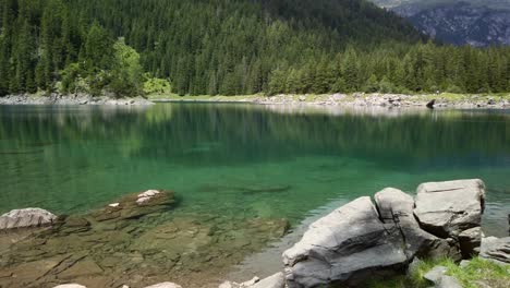 rocky beach of the obernberger lake in tyrol with turquoise colored water and a forest in the background