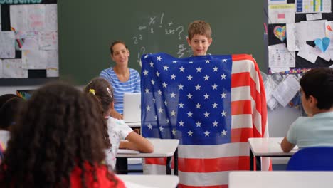 Vista-Frontal-De-Un-Colegial-Caucásico-Explicando-Sobre-La-Bandera-Estadounidense-En-El-Aula-4k