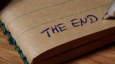 person writing the end at the end of notebook, close up view