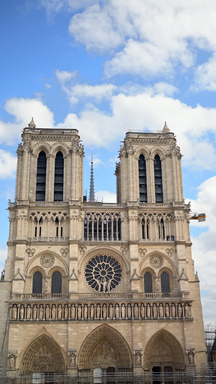 Paris, Fransa'daki Notre Dame Katedrali'nin yeniden inşa edilen cephesi ve arka planda mavi gökyüzü. Dikey