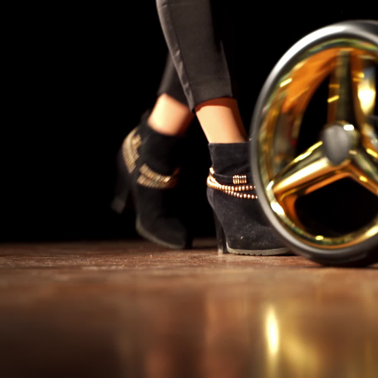 Female legs step back and pull the baby stroller. New modern baby pram in the darkness of the room. Dark backdrop