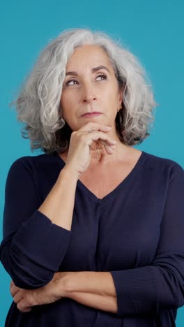 mature woman in deep thought against blue background
