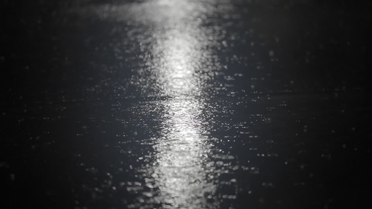 Closeup of Rain Splashing on Wet Pavement at Night