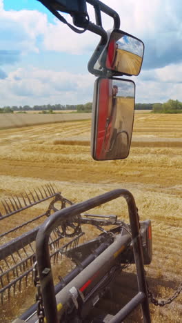 close-up combine working in summer. detail of grain harvester collecting ripe wheat on the field. part of agricultural machine in a bright day. vertical video