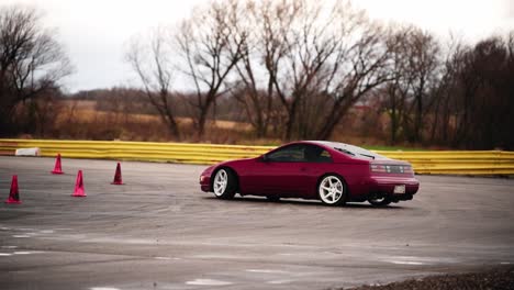 red car sliding in slow motion along red cones and on asphalt