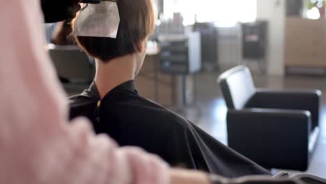 Hands-of-caucasian-male-hairdresser-highlighting-client's-hair-in-foil-at-salon,-in-slow-motion