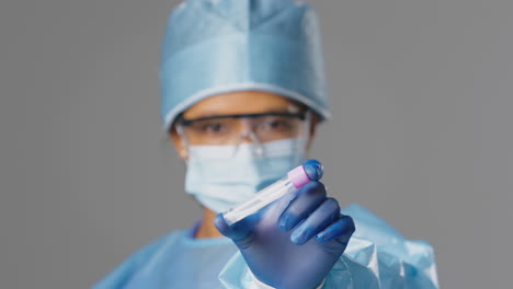 trabajadora de investigación de laboratorio con ppe y gafas de seguridad sosteniendo un tubo de ensayo de pcr con un hisopo