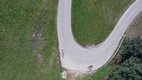 drone shot from above showing cyclists on a rural road surrounded by lush greenery.