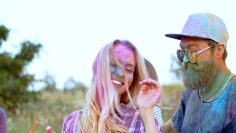 joven pareja alegre bailando y divirtiéndose al aire libre en las coloridas pinturas en polvo en el festival holi