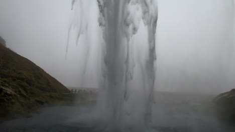 toma cinematográfica detrás de la cascada islandesa seljalandsfoss y donde el agua rompe con fuerza