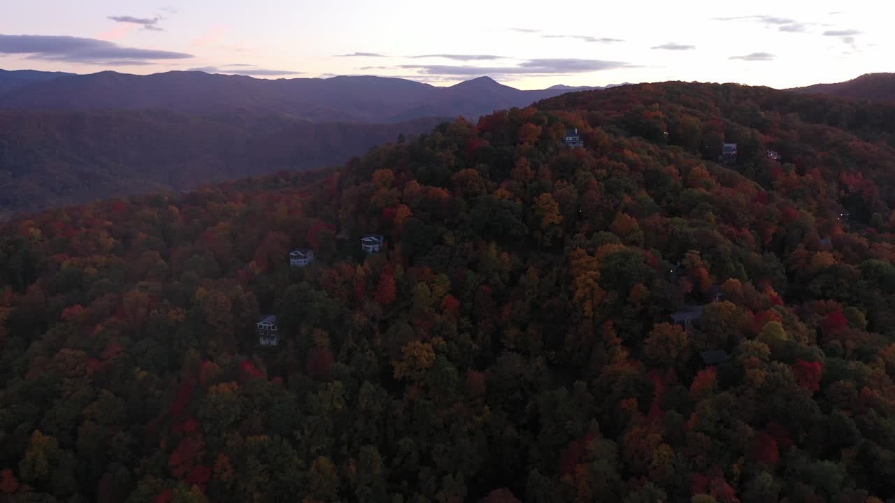 cinematográfica aérea de las montañas humeantes y cabañas en colores de otoño, forja de palomas, tn