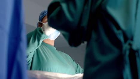 Diverse-female-and-male-surgeons-in-masks-passing-surgical-tools-during-operation,-slow-motion