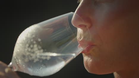 Close-up-of-beautiful-female-lips-taking-sip-from-champagne,-golden-sunlight