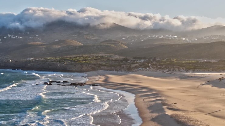 Aerial view of Portugal's coast with waves and mountains in the background