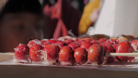 making fruits in boiling caramel close-up. chinese winter sweet dessert tanghulu street food.berries, grapes, tangerine and others fruit caramelized in sugar. asian street market with traditional food.. high quality 4k footage