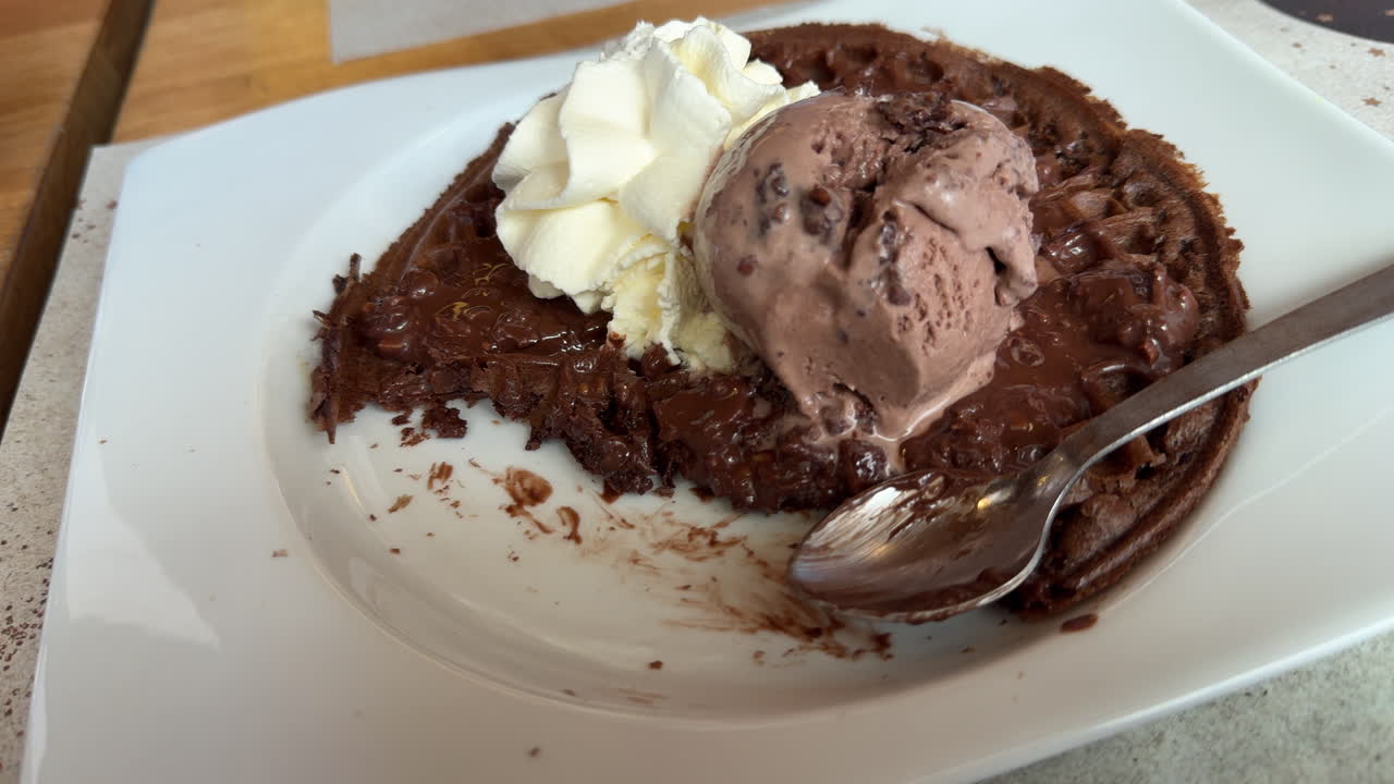 Warm chocolate waffle topped with ice cream, filmed in close-up
