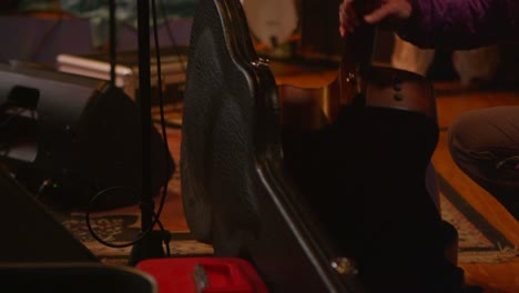 a woman takes a guitar out of a case as musicians prepare to play