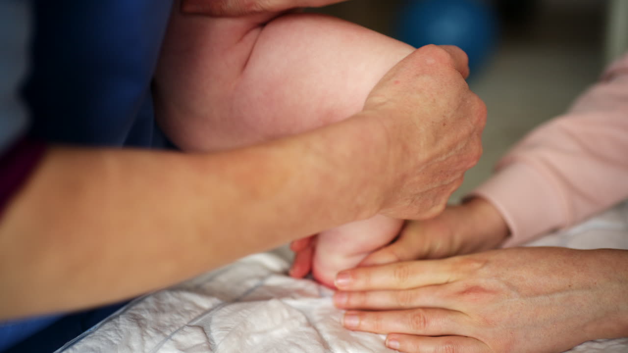 Close up of adult hands gently massaging a baby's foot and sole