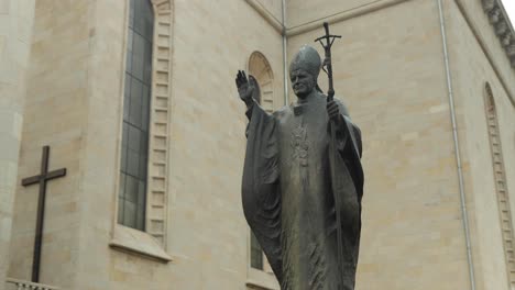 a statue of the pope next to a renovated church in katowice, poland