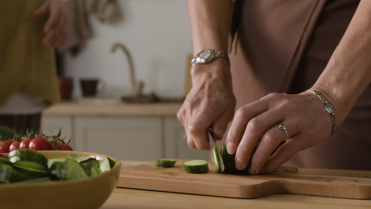 A woman cutting cucumber on a wooden board