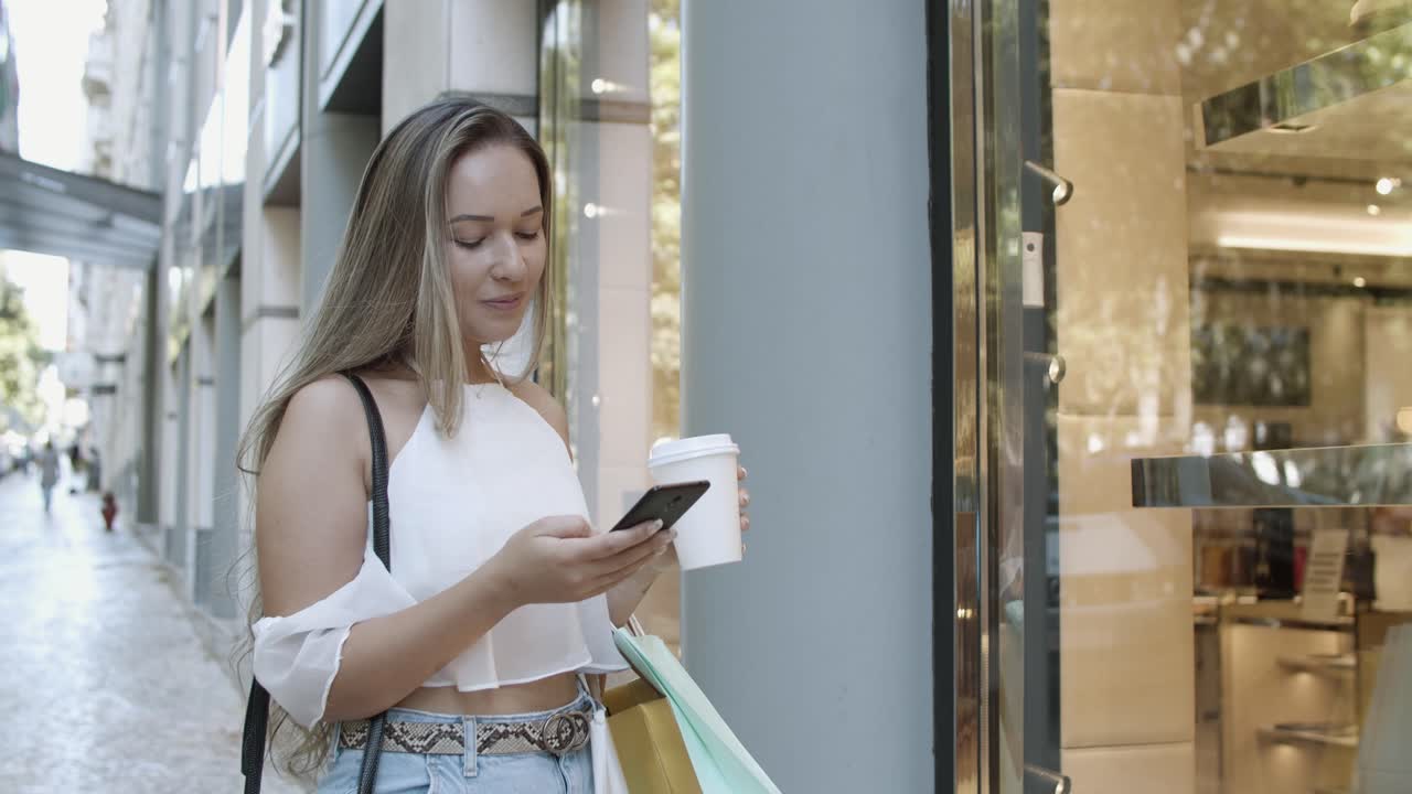 mujer caucásica escribiendo en el teléfono inteligente, leyendo chat y sonriendo