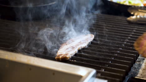 chef slaps raw slices of beef bulgogi onto sizzling grill creating smoke and steam, slow motion hd