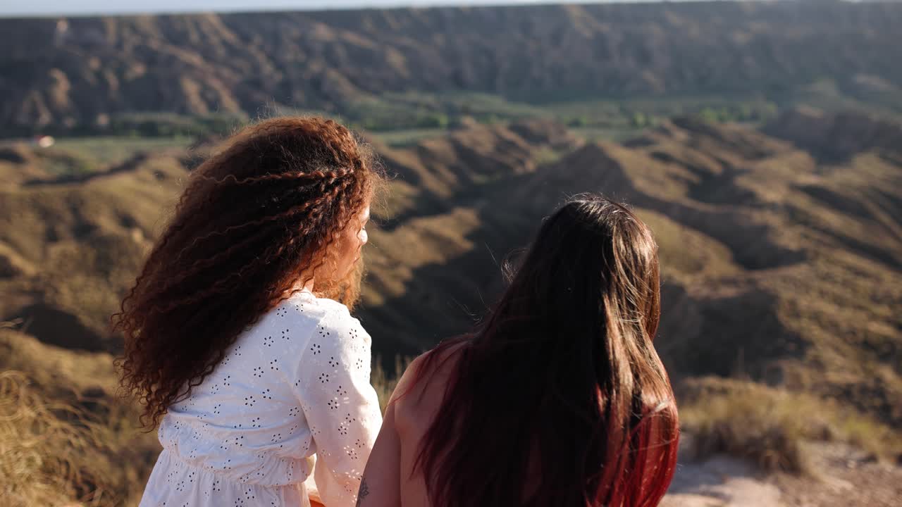 Two women admiring a scenic desert landscape from a high vantage point